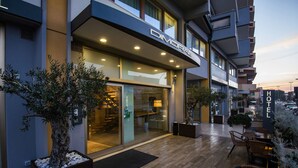 Un hotel moderno con fachada de vidrio, zona de estar al aire libre y un jardín bien cuidado.