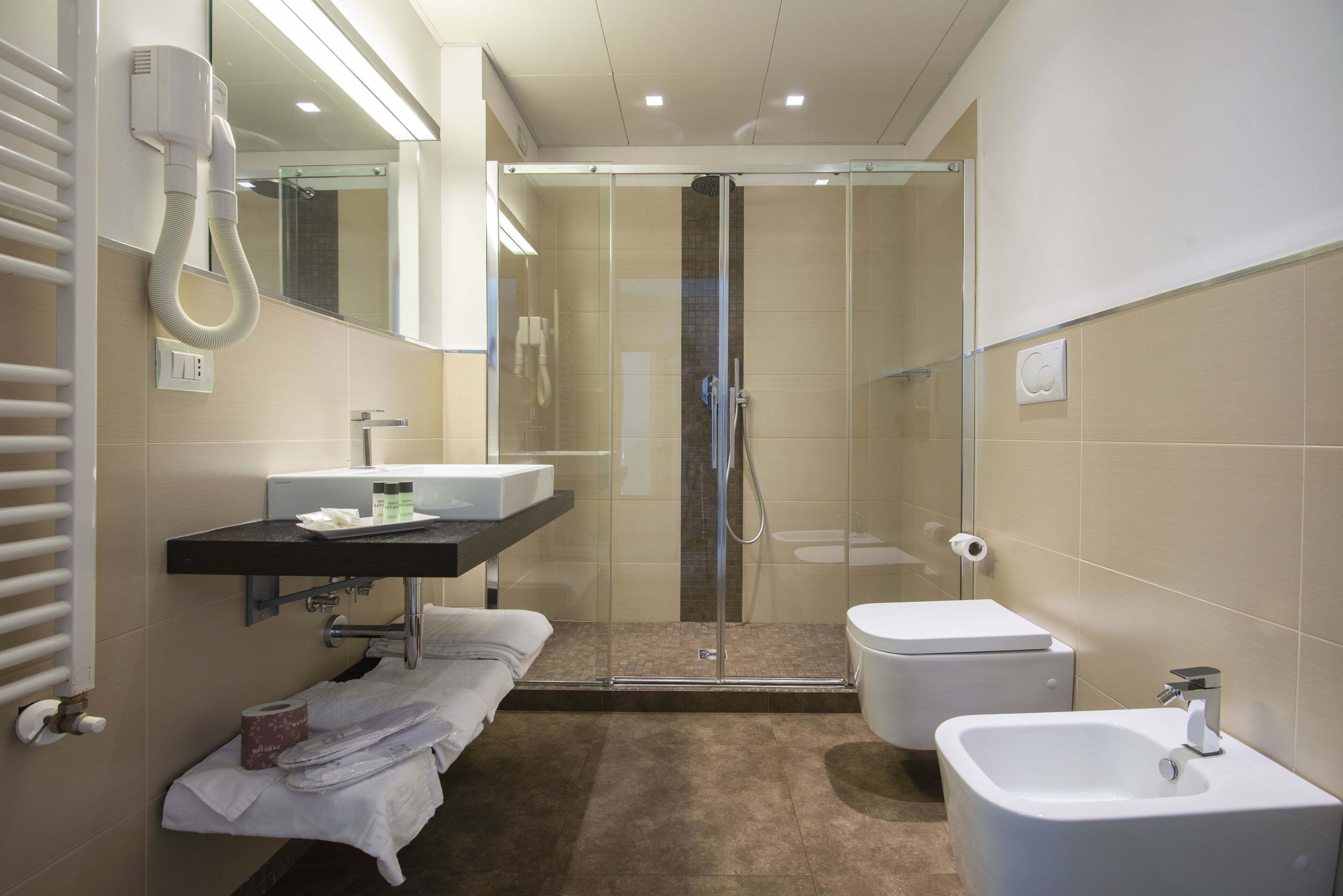 Une salle de bain moderne avec une douche à parois de verre, un lavabo blanc et un bidet.