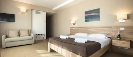 A modern hotel room with a bed, a sofa, and a TV.