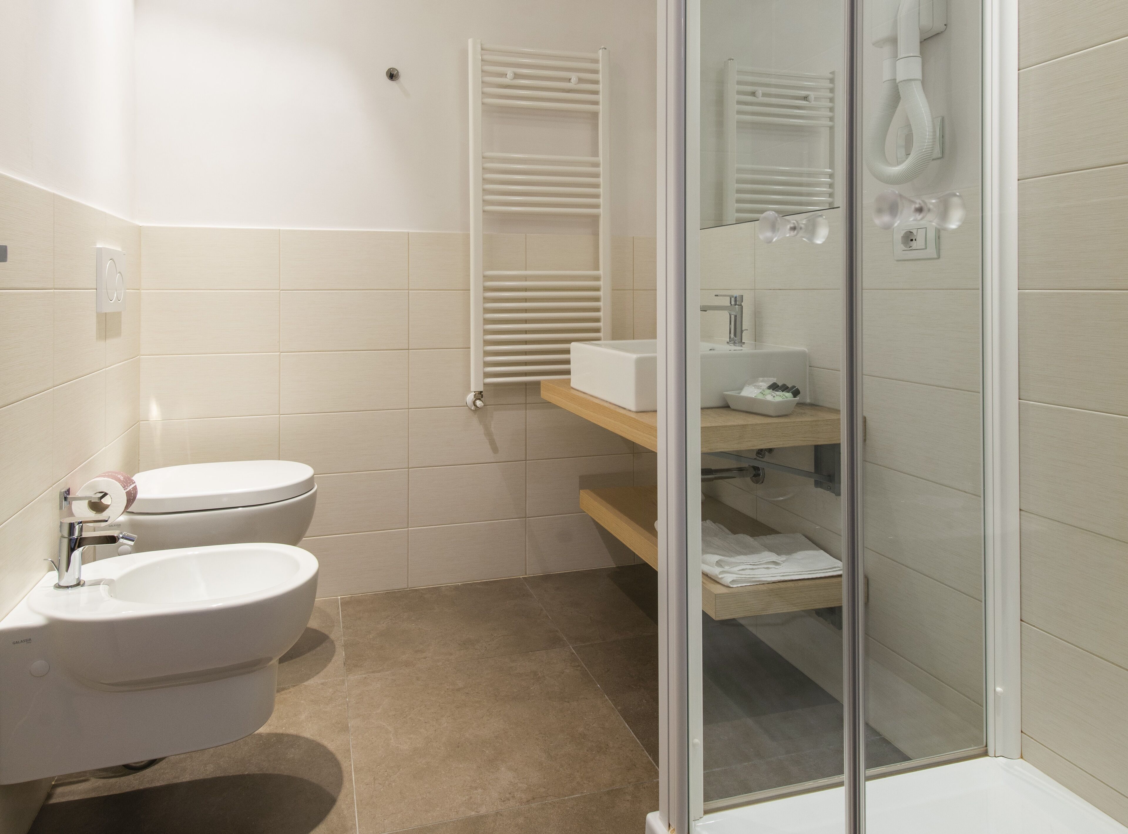 Une salle de bain moderne équipée de toilettes, d’un bidet et d’une douche à parois de verre.