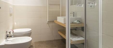 Une salle de bain moderne équipée de toilettes, d’un bidet et d’une douche à parois de verre.