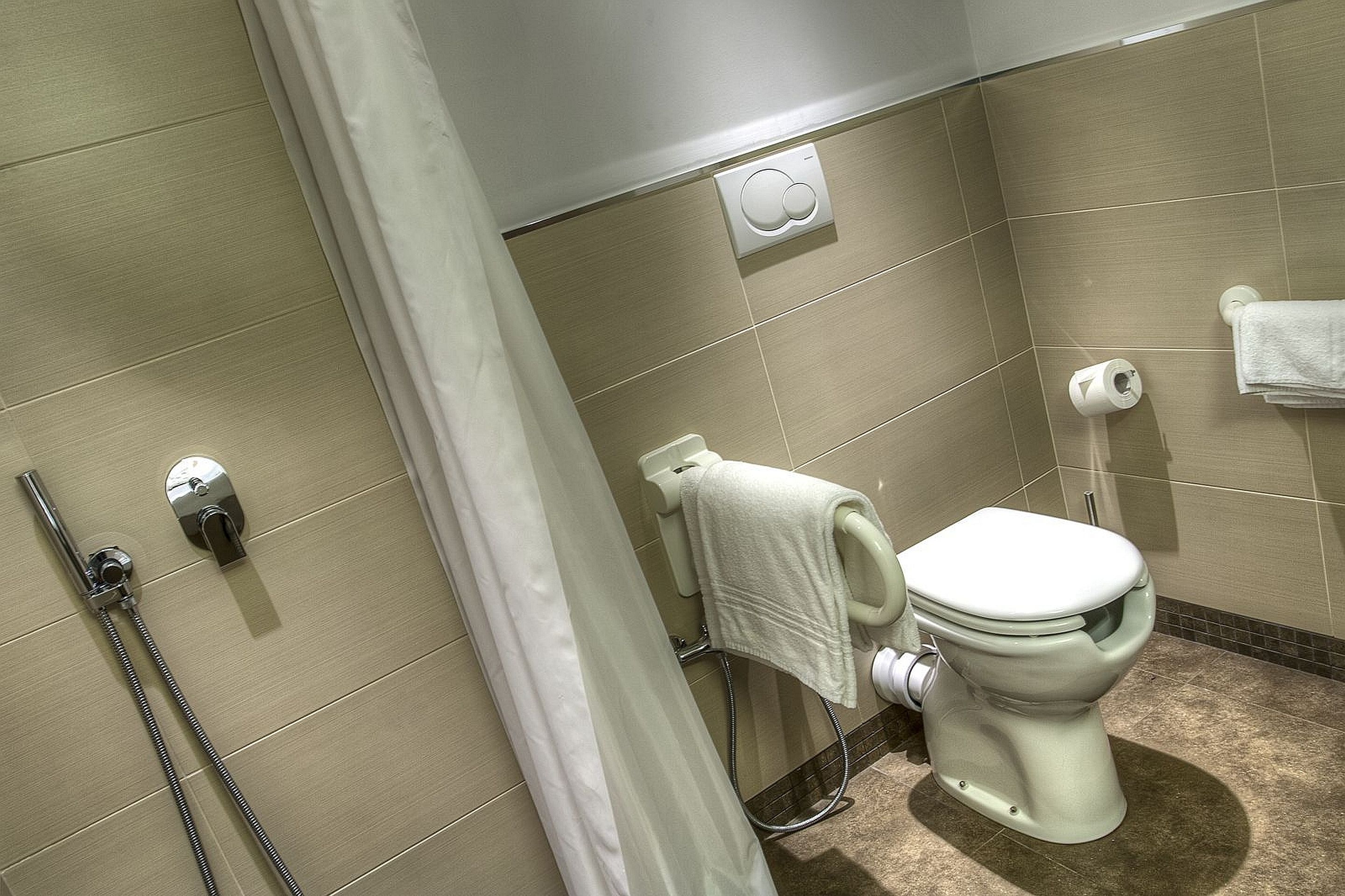 Une salle de bain équipée de toilettes, d’une douche et d’un porte-serviettes.