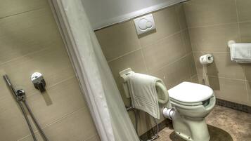 Un baño con inodoro, ducha y perchero para toallas.