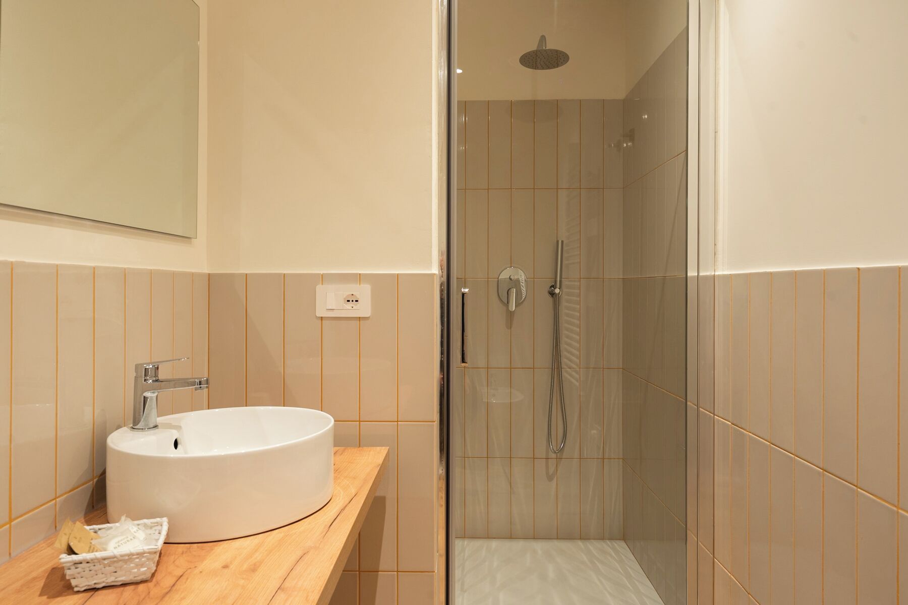 A modern bathroom with a white sink, wooden countertop, and a glass-enclosed shower area.
