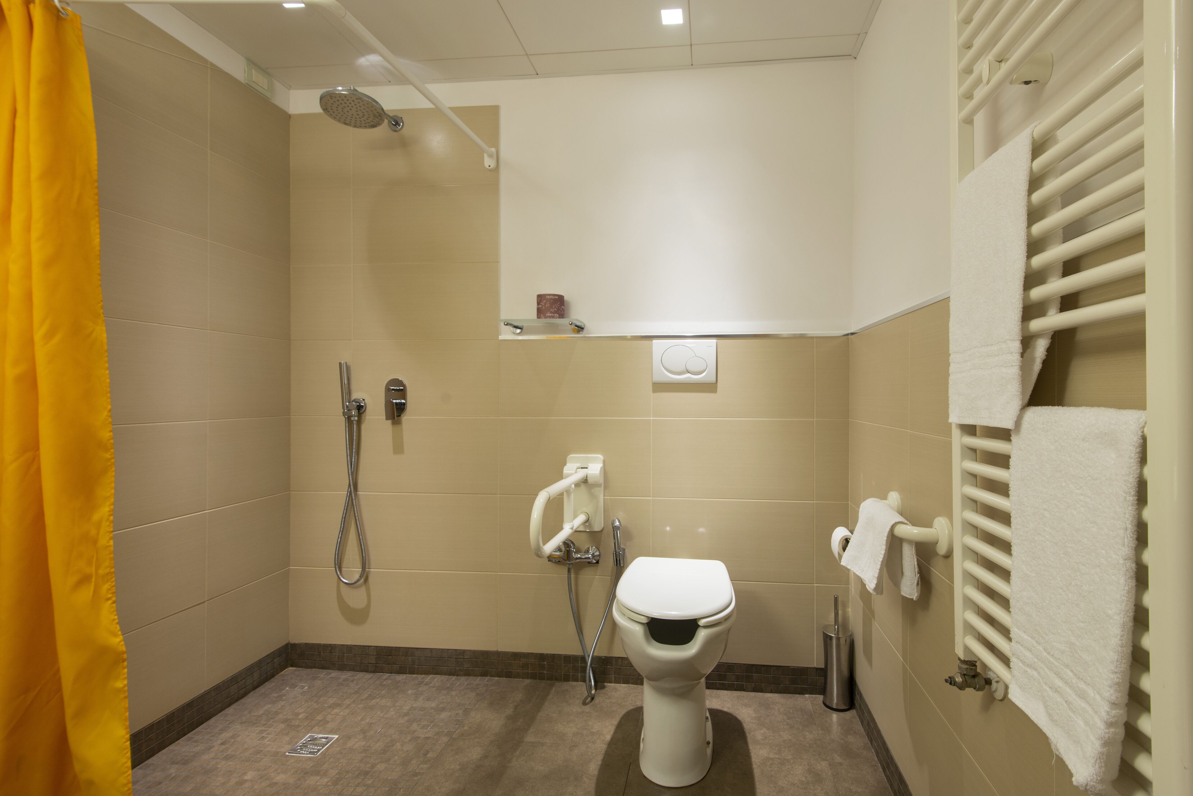 A small, modern bathroom with a shower, toilet, and towel rack.