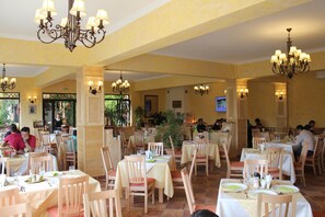 Un restaurante con varias mesas y sillas, candelabros y vistas al exterior.