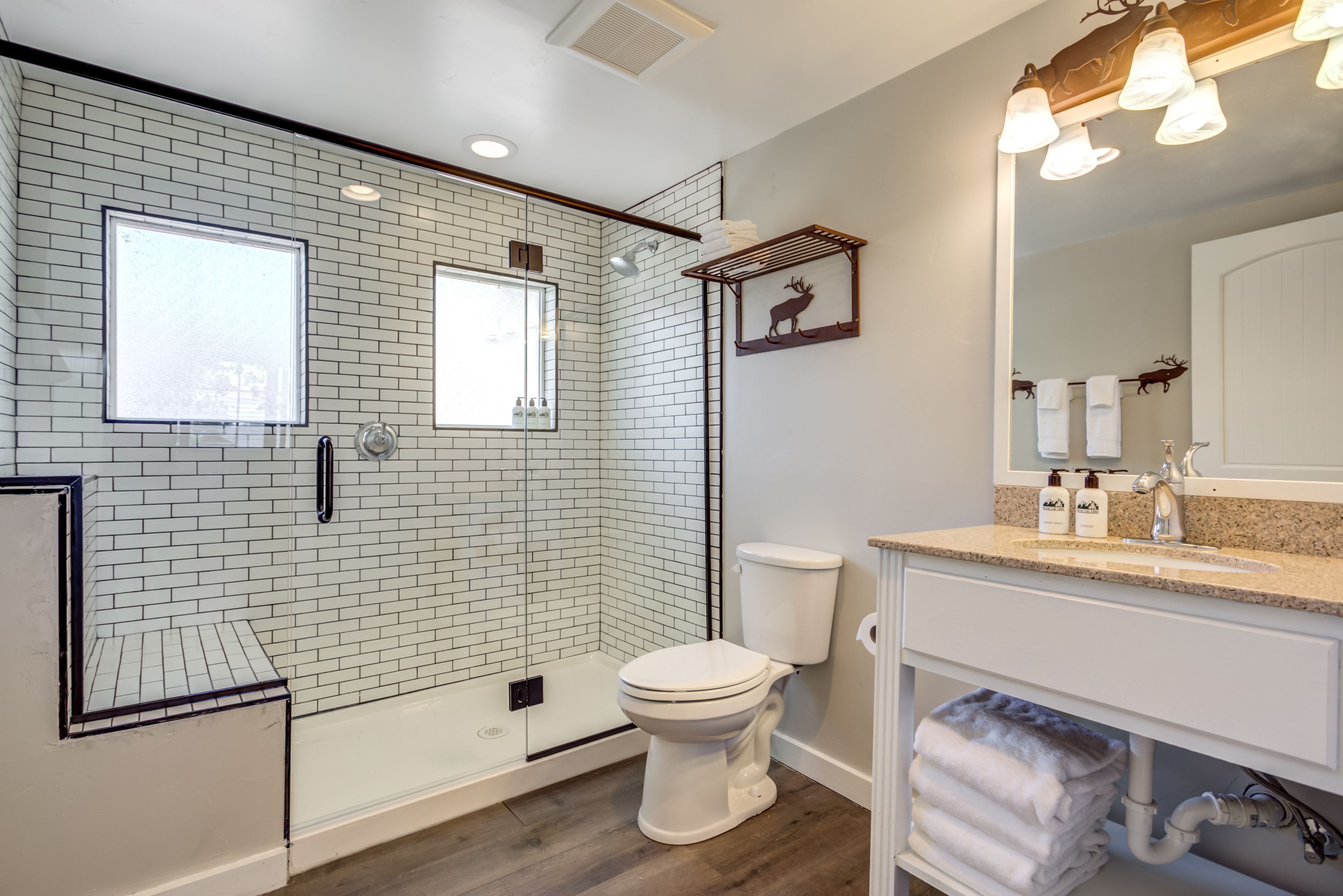 Un baño moderno con cabina de ducha de vidrio, inodoro blanco y tocador con lavabo y espejo.
