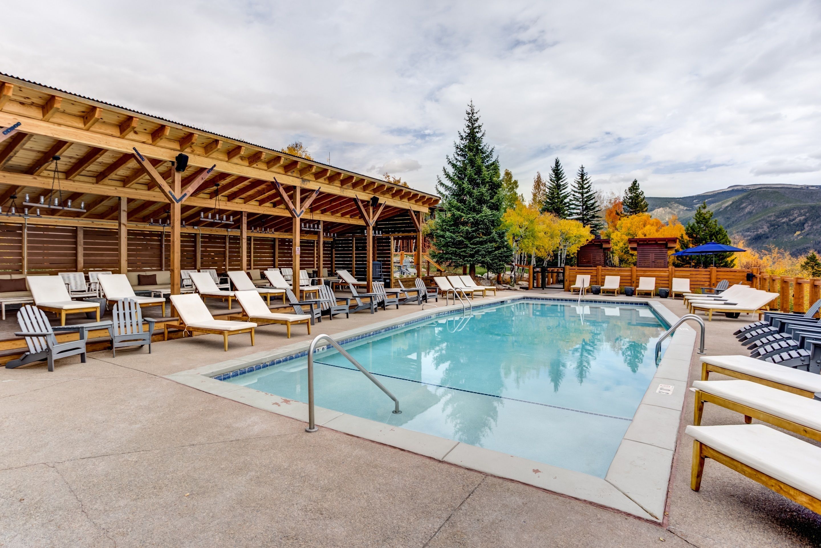 A pool area with lounge chairs and a covered seating area.