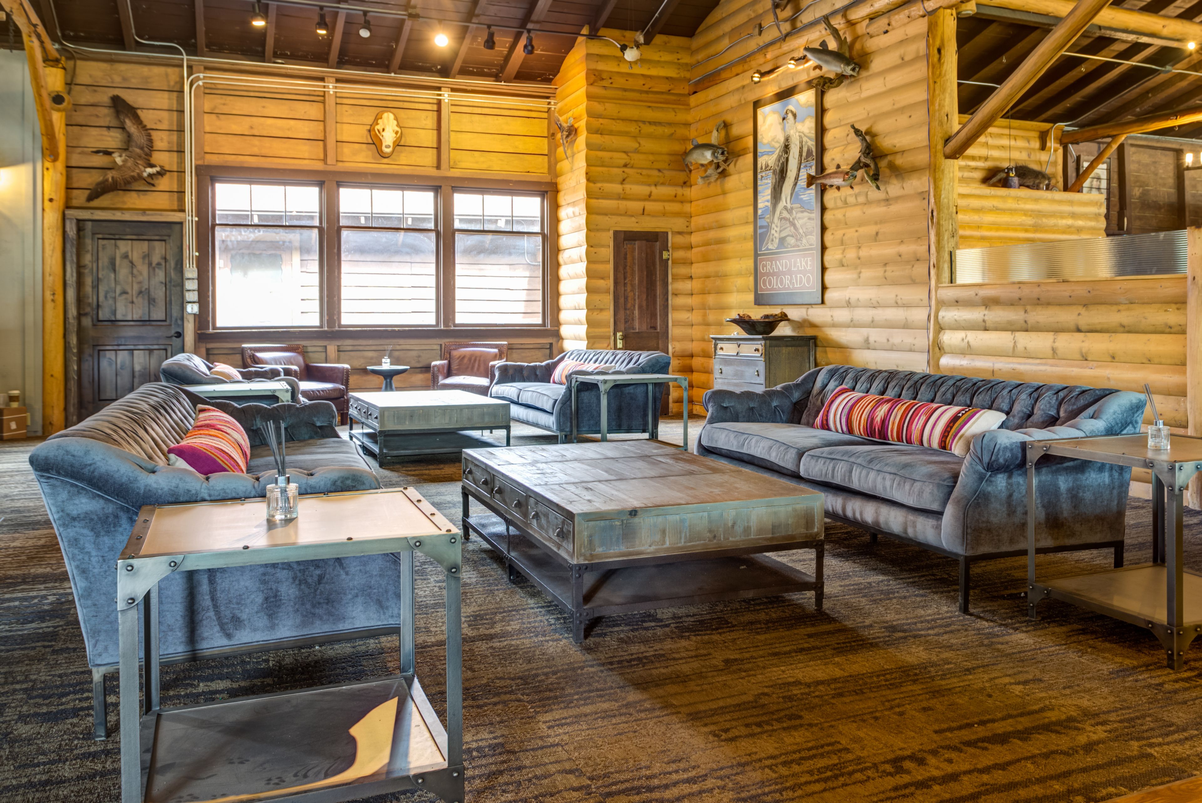 A log cabin-style interior with rustic furniture, large windows, and a wooden ceiling.