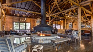 A spacious lodge interior with a stone fireplace, wooden furniture, and a high ceiling with exposed beams. - Grand Lake Lodge (Grand Lake)