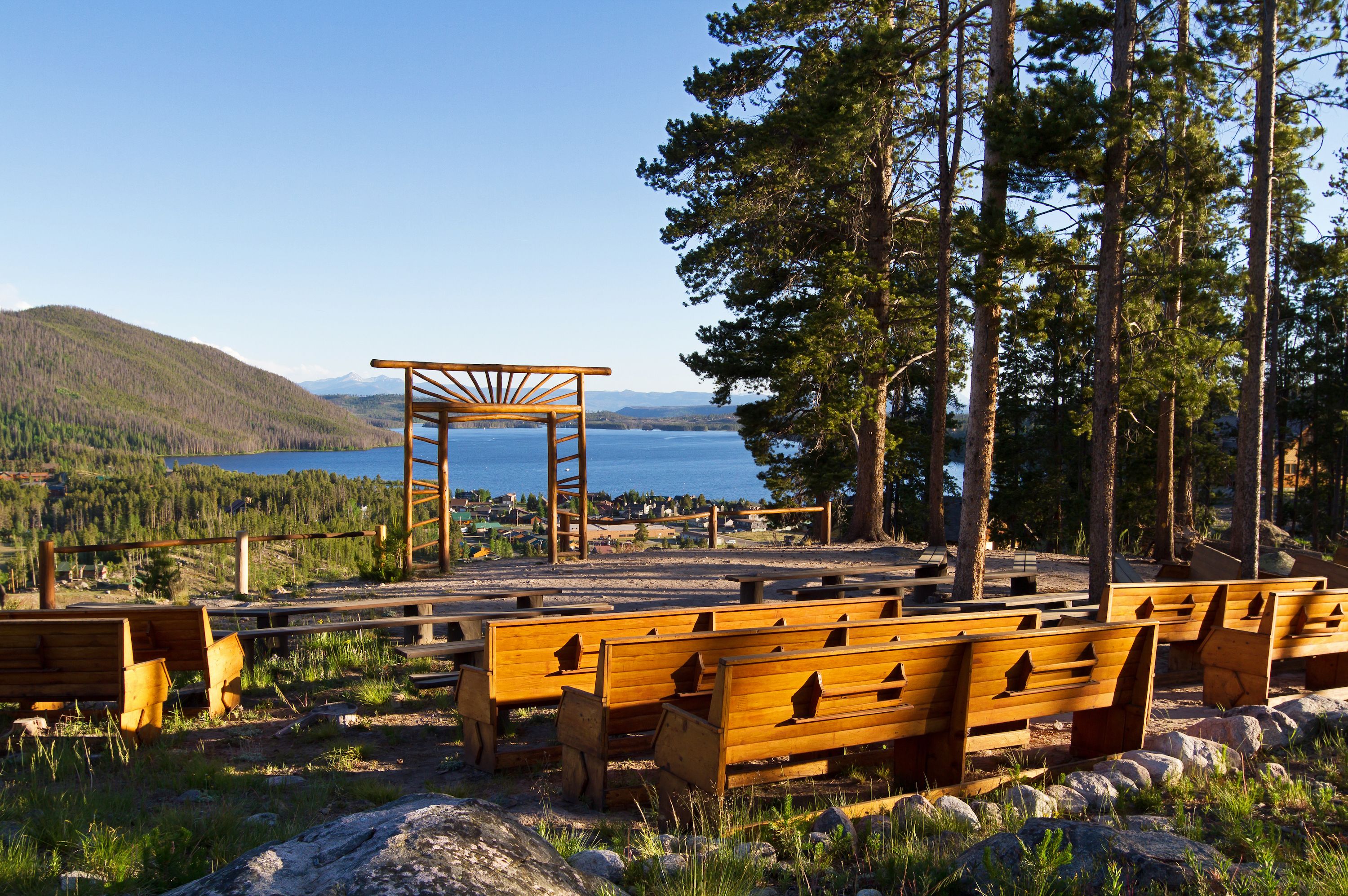 Un espace avec des bancs en bois offrant une vue sur un lac et des montagnes.