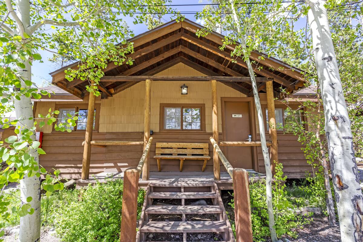 Une cabane en bois avec un escalier en bois menant à un banc et à une porte.