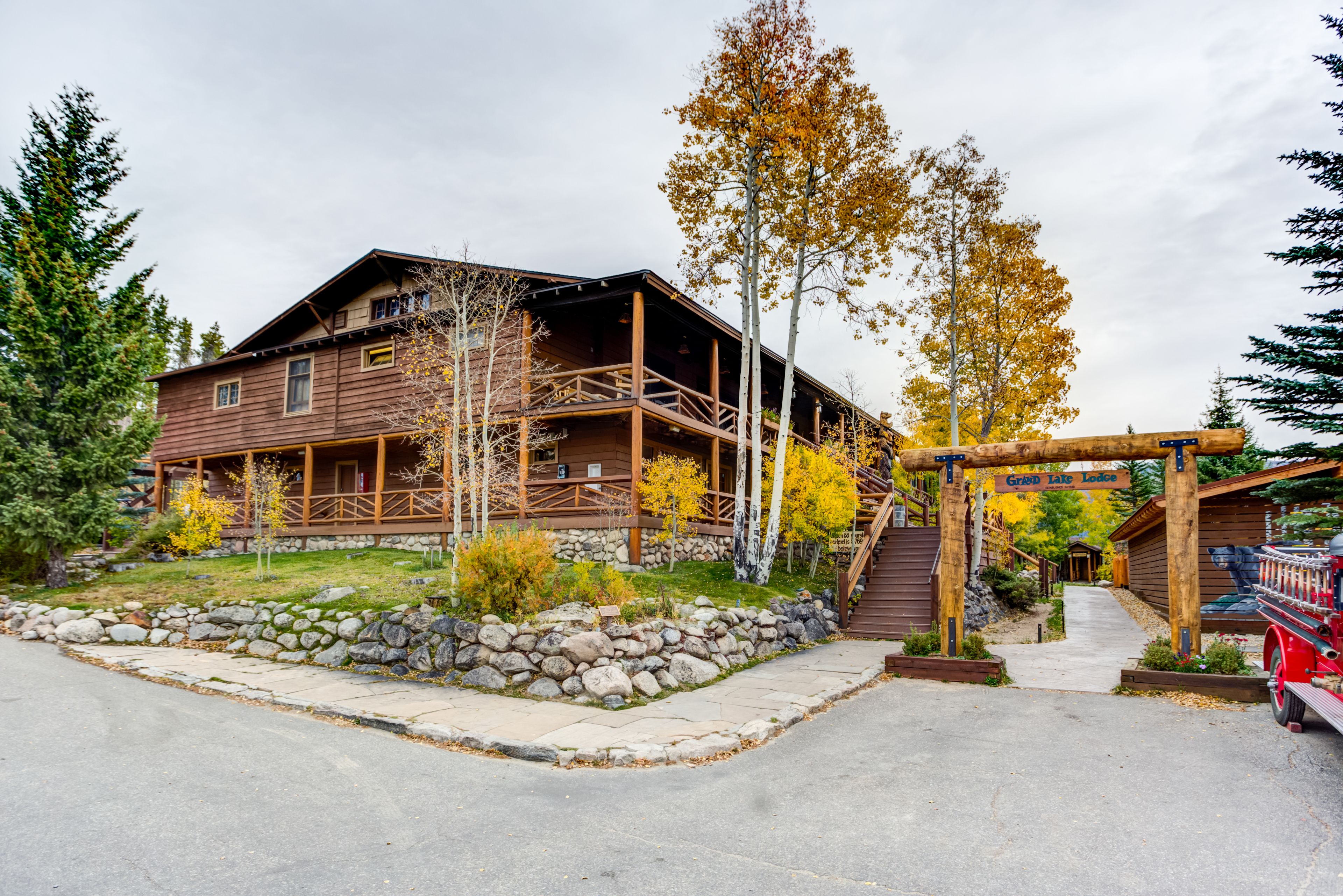 A rustic lodge with a stone foundation, wooden deck, and a covered porch.