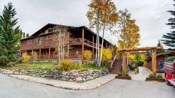 A rustic lodge with a stone foundation, wooden deck, and a covered porch.