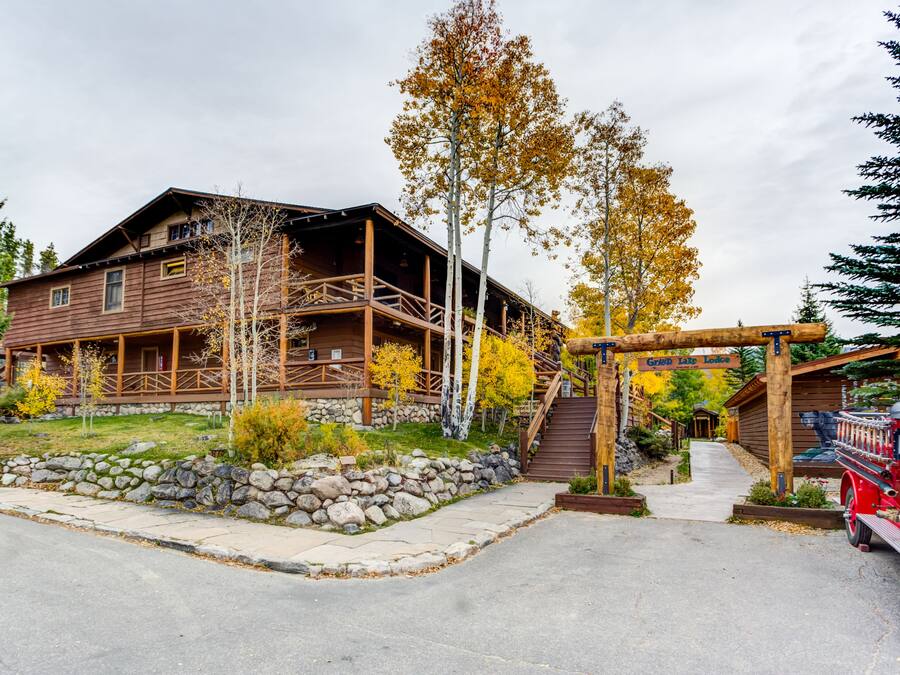 A rustic lodge with a stone foundation, wooden deck, and a covered porch.