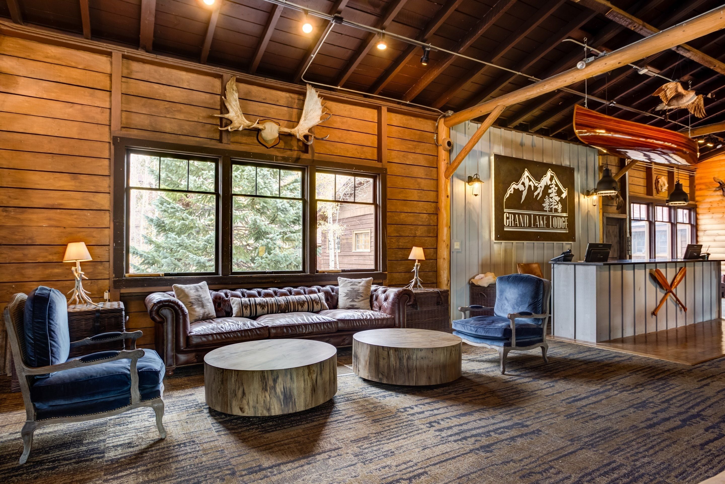 A cozy lodge interior with a leather sofa, two round coffee tables, and a reception desk.