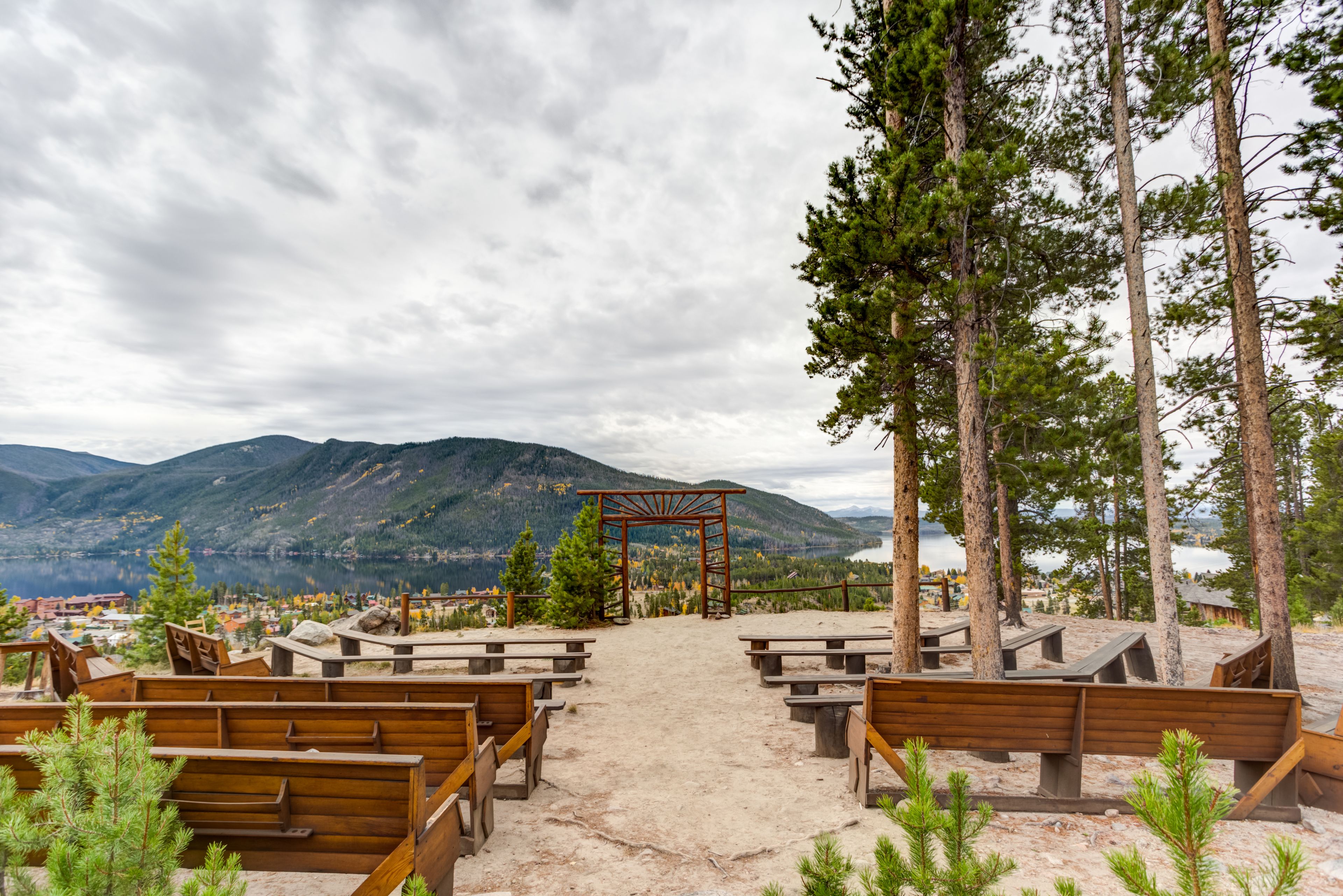 A wooden bench area with a view of mountains and a lake.