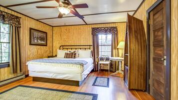 A bedroom with a bed, a ceiling fan, a window with curtains, a chair, and a door.