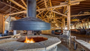 A rustic interior with a stone fireplace, wooden beams, and a large chimney. - Grand Lake Lodge (Grand Lake)
