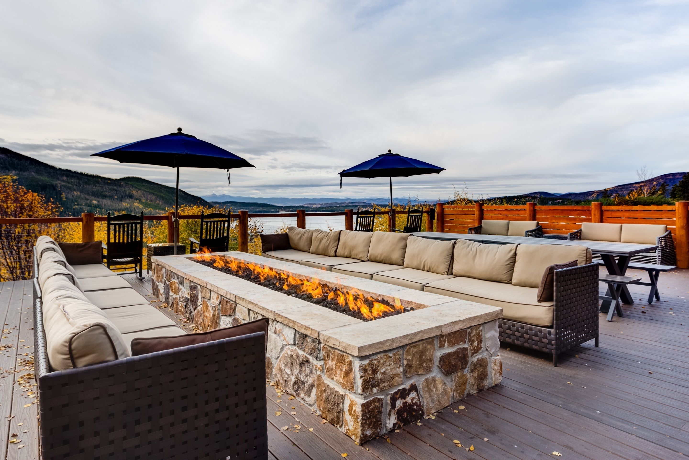 Une terrasse extérieure dotée d’un foyer en pierre, de sièges confortables et de parasols.