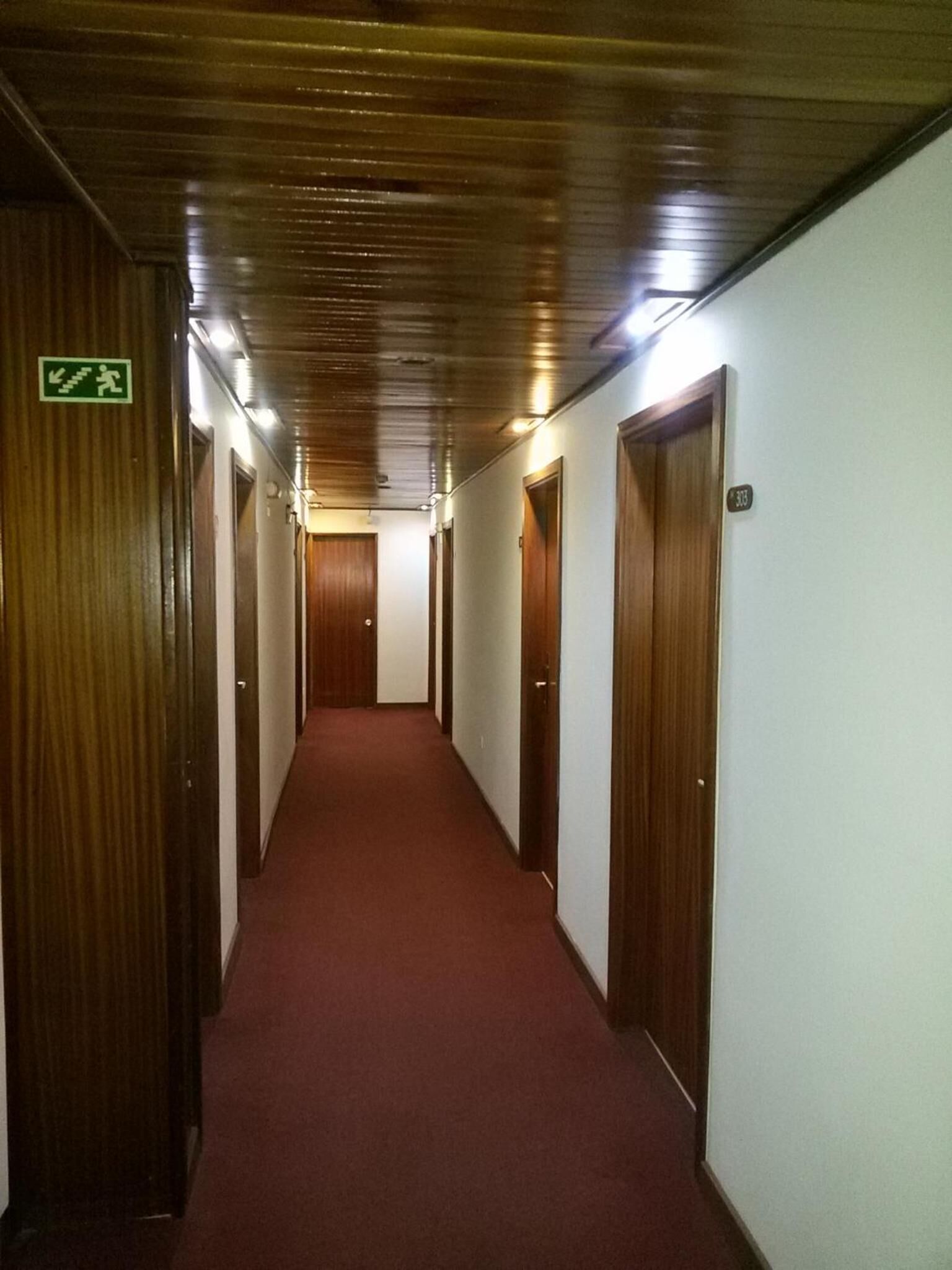 A long, narrow hallway with wooden doors on both sides and a red carpet.