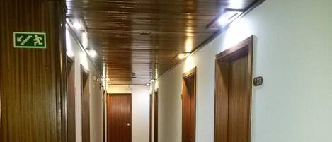 A long, narrow hallway with wooden doors on both sides and a red carpet.