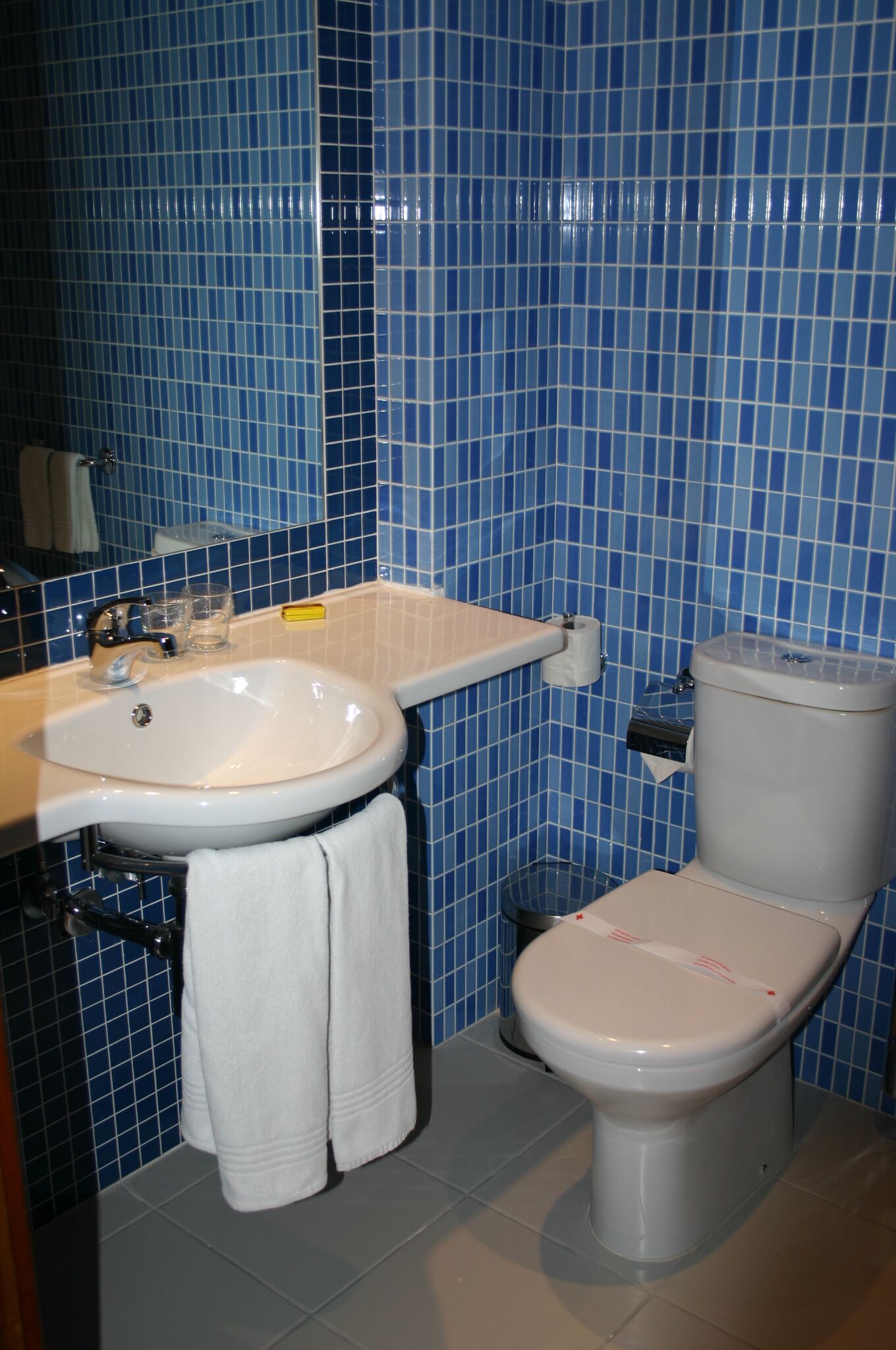 Un baño con lavamanos blanco, inodoro y paredes de azulejos azules.