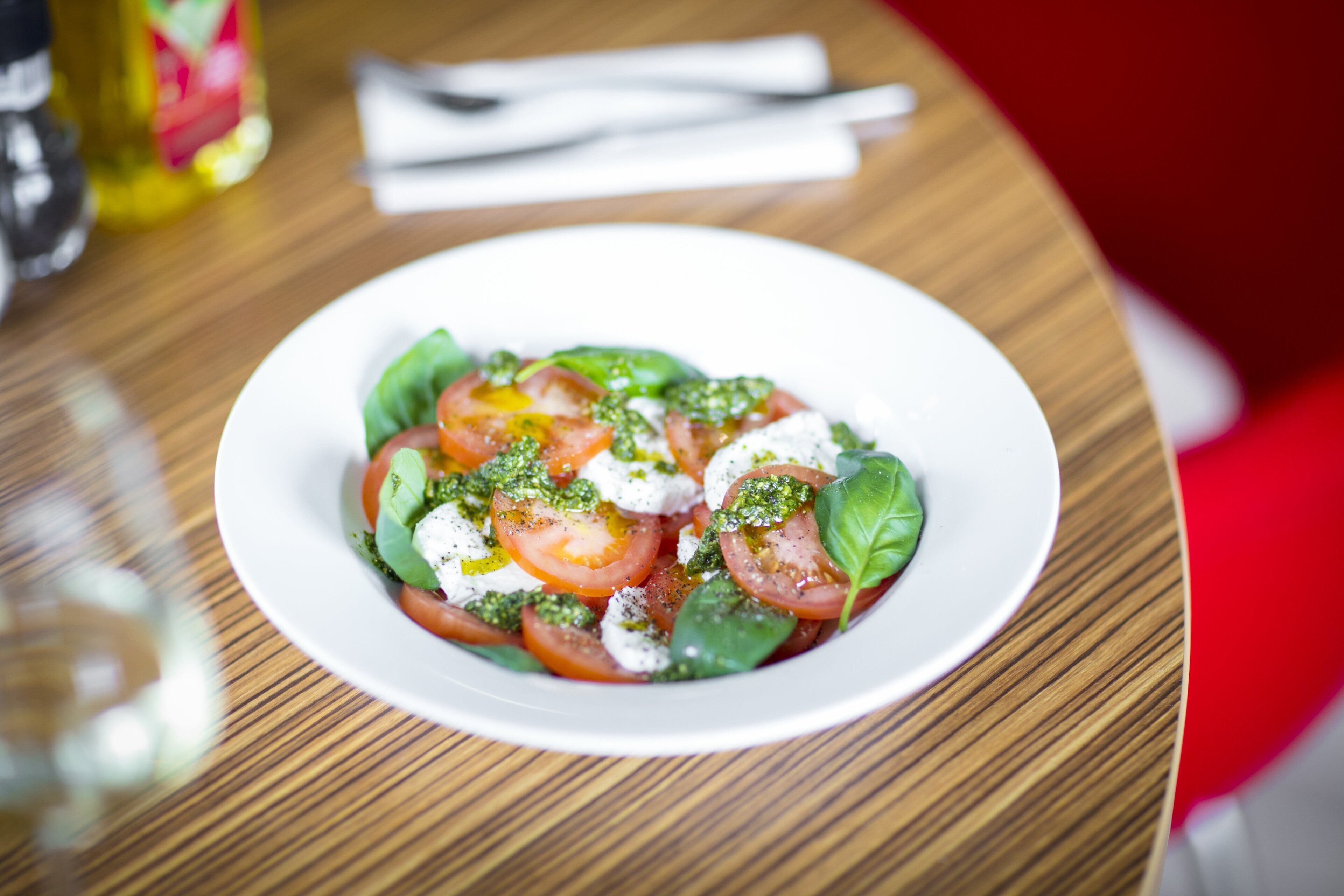 A plate of food with tomatoes, basil, and mozzarella on a wooden table.