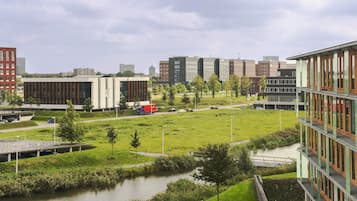 A modern building complex with a grassy area and a small water body.