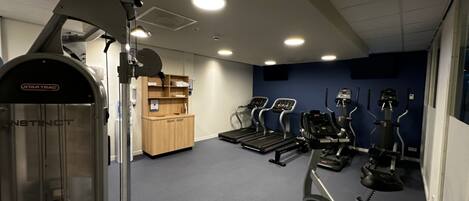 A gym with treadmills, elliptical machines, and weightlifting equipment.