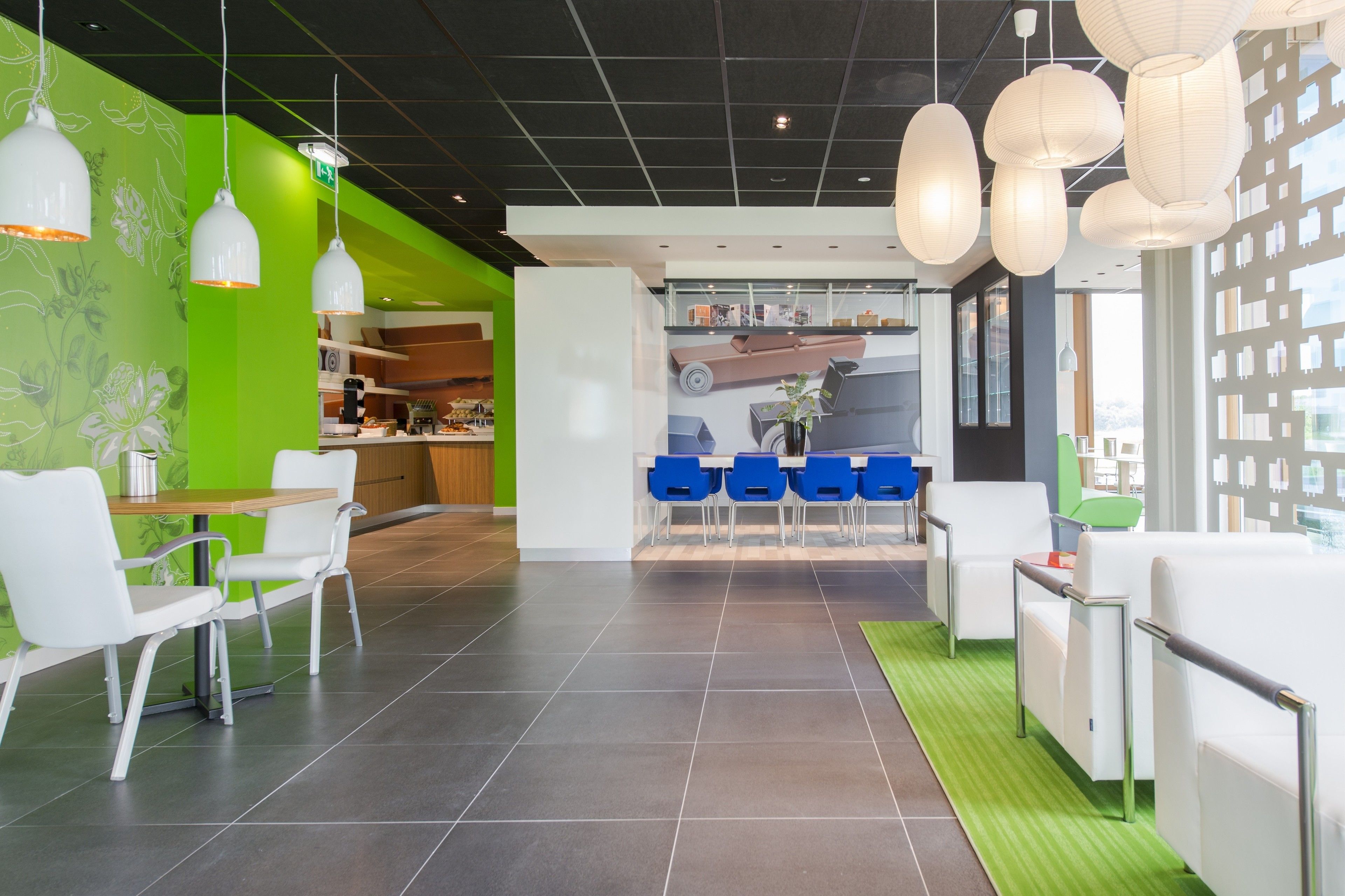 A modern interior with a green accent wall, white furniture, and hanging pendant lights.