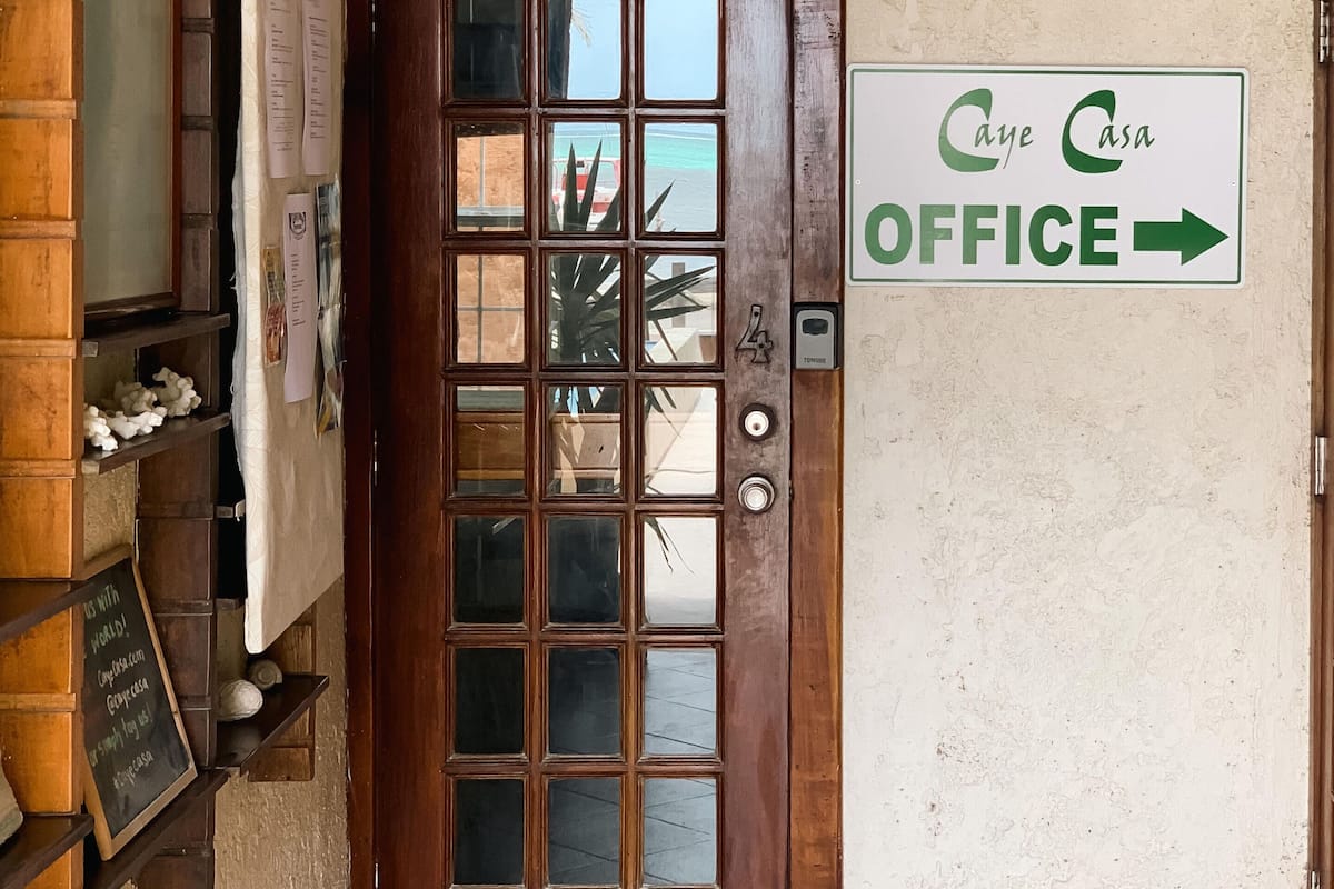 A wooden door with a glass panel and a sign indicating the office direction.