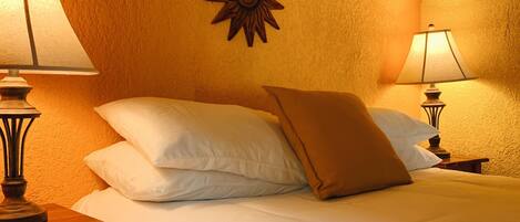 Une chambre d’hôtel comprenant un lit, deux lampes de chevet, un élément décoratif en forme de soleil fixé au mur et un mur à texture.