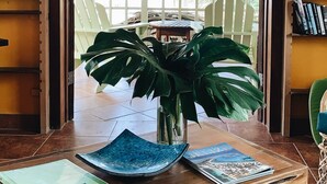 A wooden table with a plant, a blue decorative plate, and a book titled "Beauza". - Caye Casa (San Pedro)
