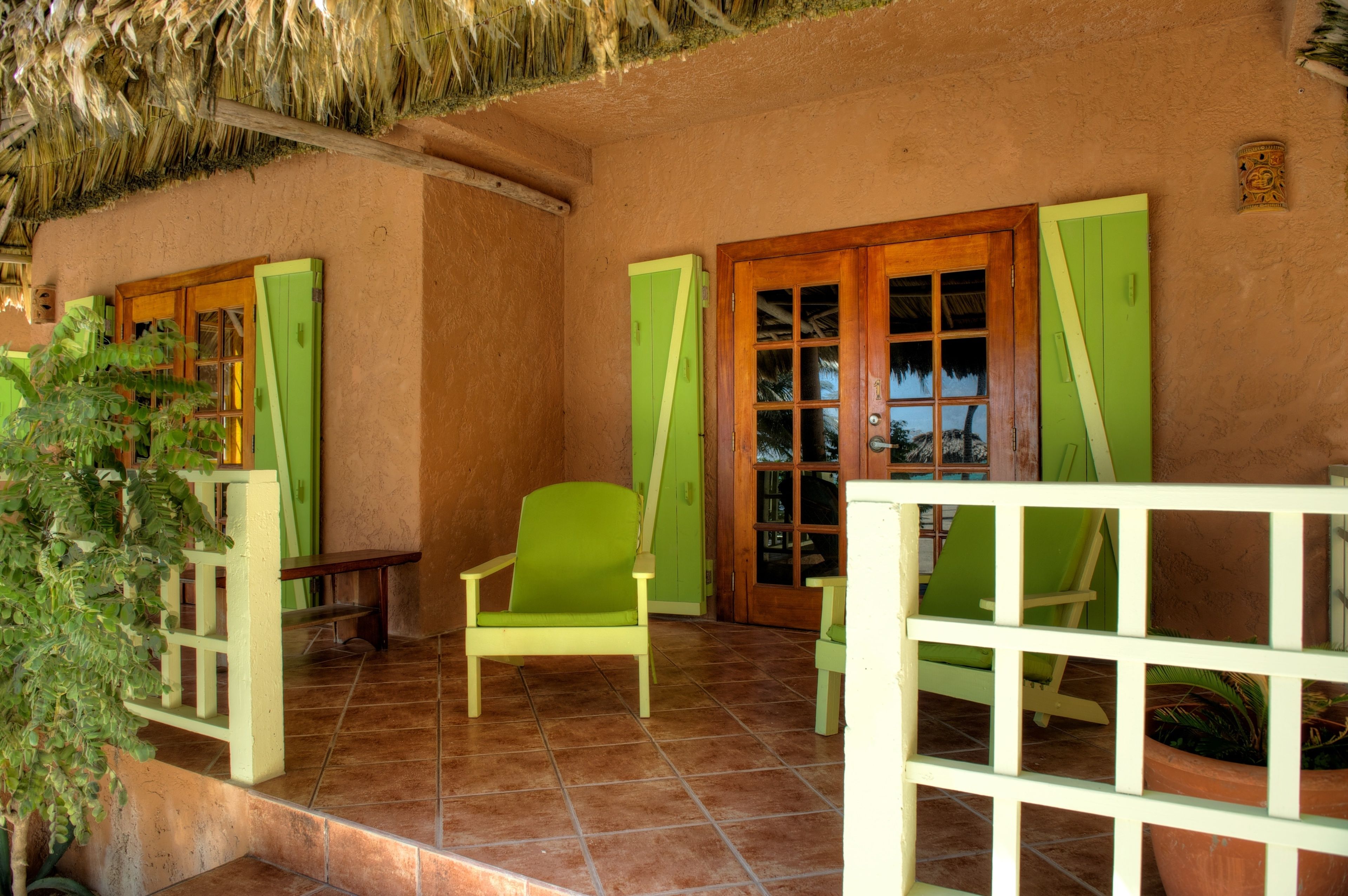 Una habitación con suelo de baldosas, puerta de madera y una silla verde.