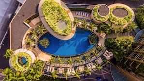 An aerial view of a resort with a central pool, surrounded by circular planters with greenery, and multiple lounge areas with sun loungers. - Grand Hyatt Kuala Lumpur (Kuala Lumpur)