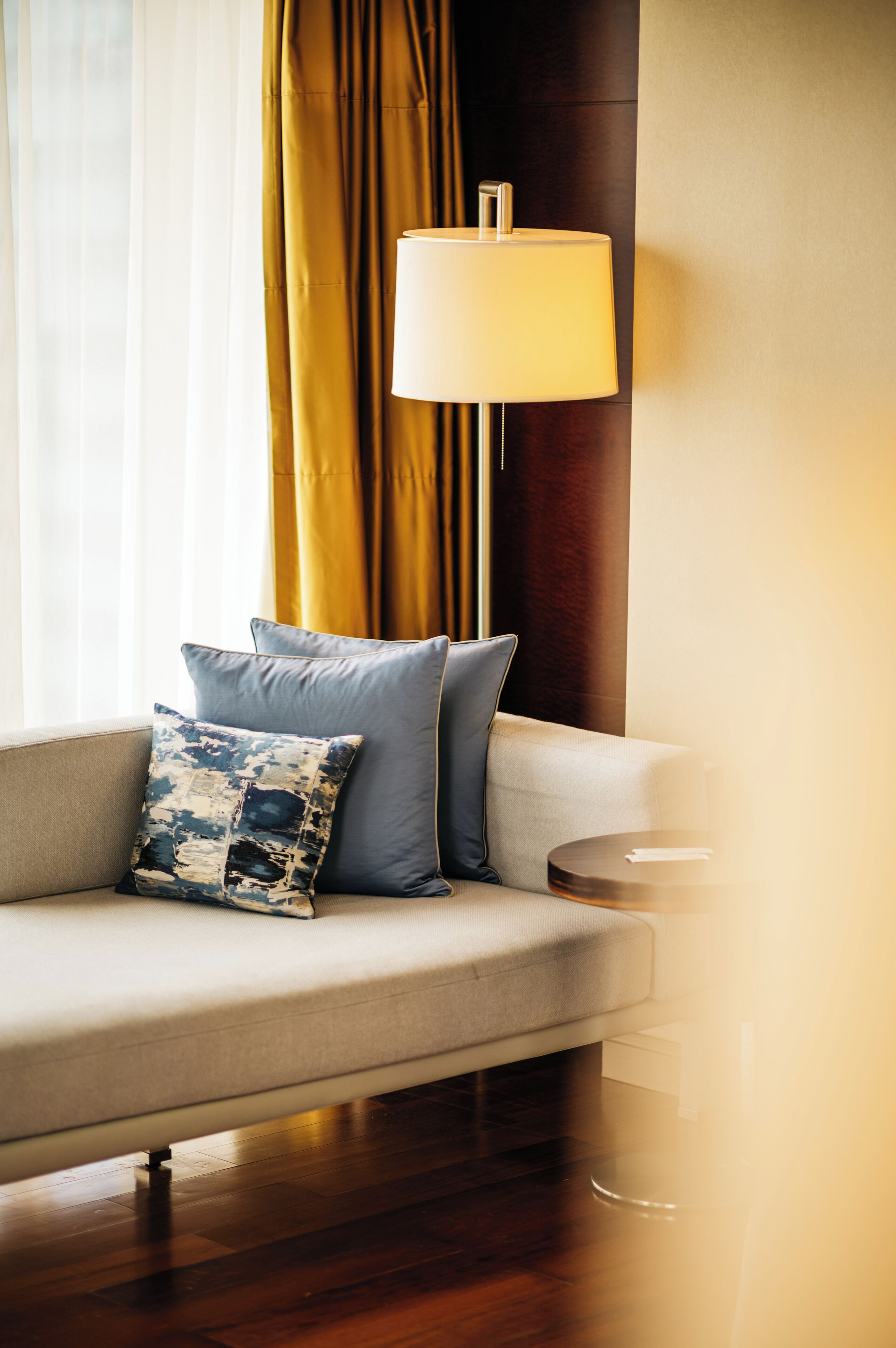 A modern living room with a sofa, two pillows, a floor lamp, and a side table.