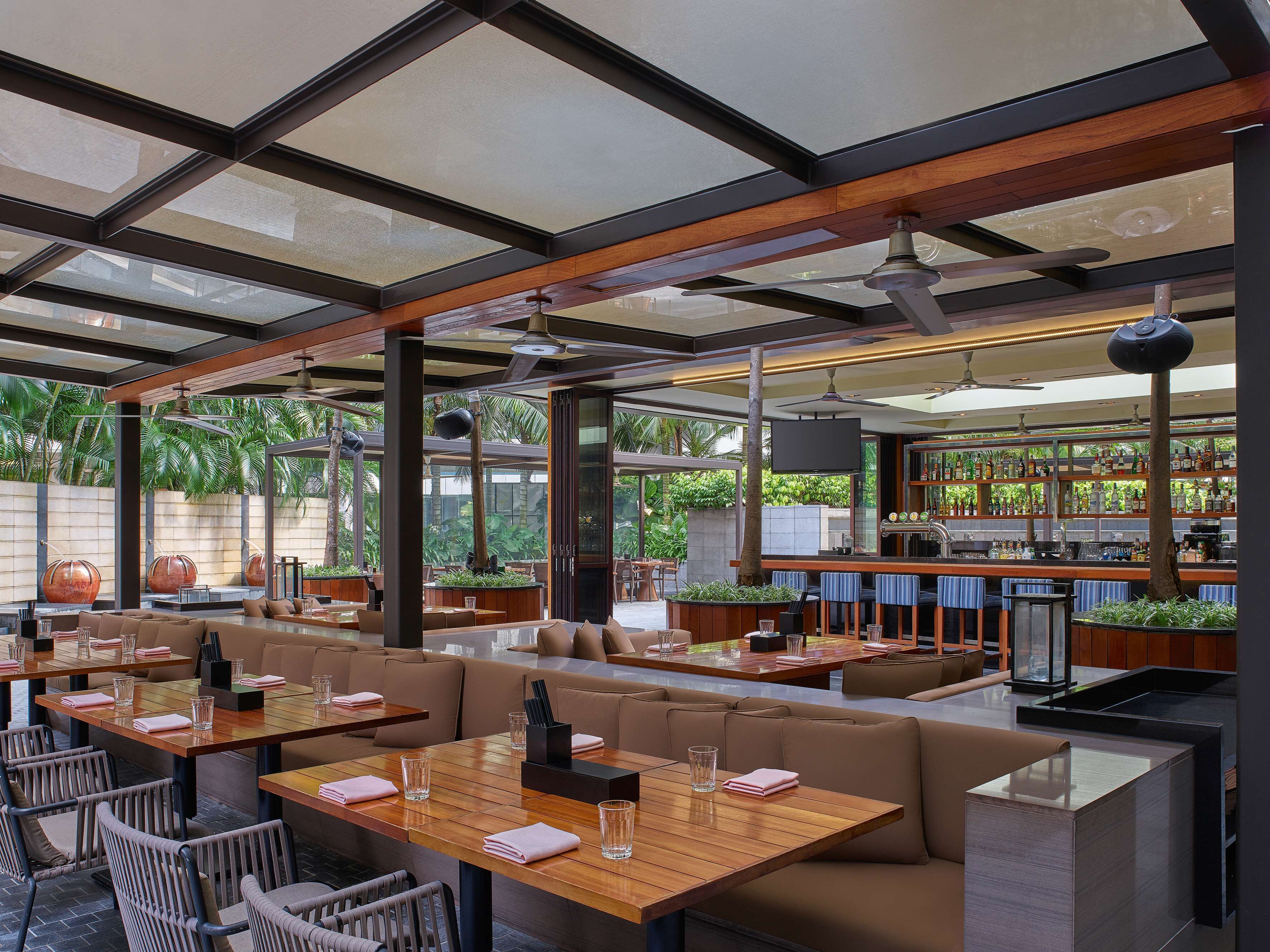 Un restaurante moderno con mesas de madera, asientos acolchados y una zona de bar.