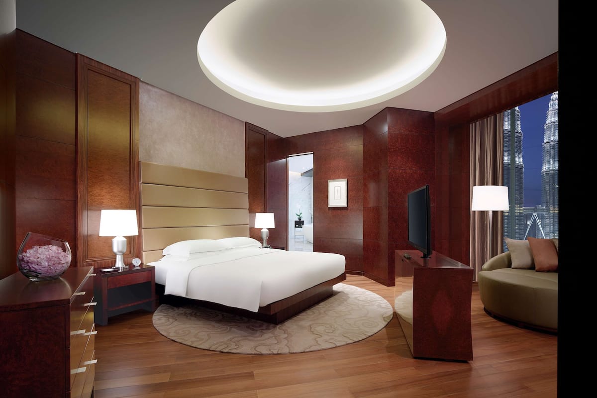 Een moderne hotelkamer met een groot bed, een bureau, een bank en uitzicht op de stad.