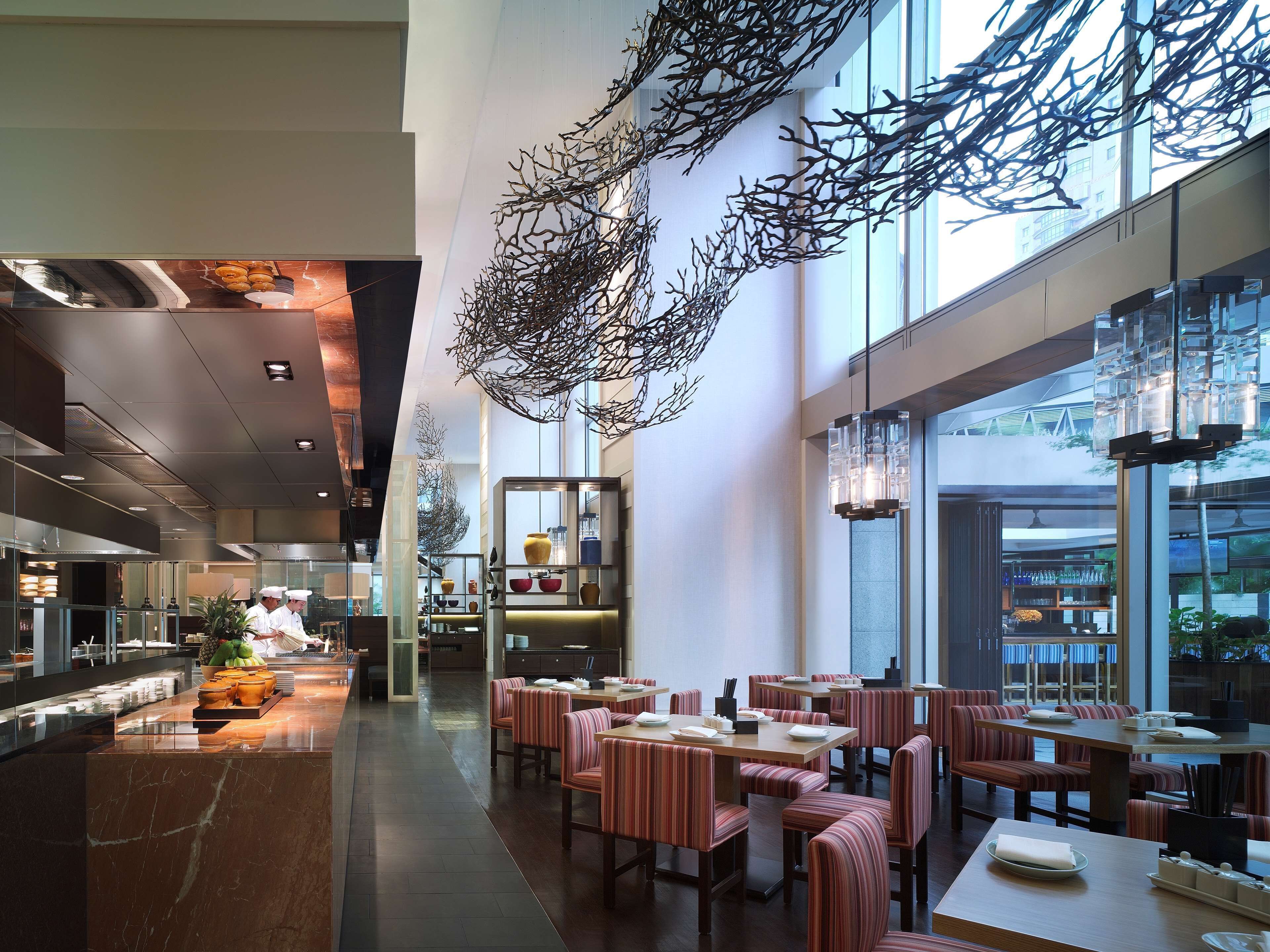 A modern restaurant with high ceilings, striped booths, and a central serving area.