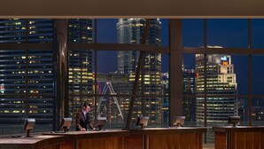 A modern reception area with a curved desk, large windows offering a cityscape view, and a digital clock displaying 7:42.