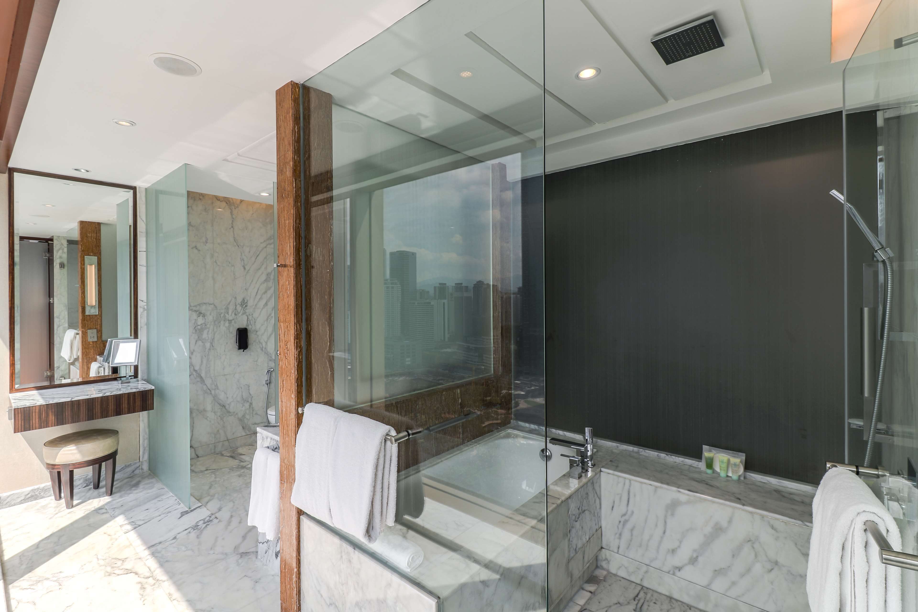 A modern bathroom with a glass-enclosed shower, a marble-tiled floor, and a large mirror.