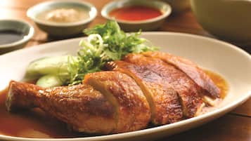 A plate of roasted duck with vegetables and sauces.