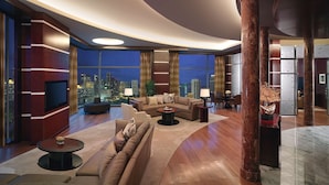 A modern living room with a curved ceiling, large windows offering a city view, a sofa, a coffee table, and a TV.