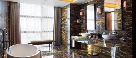 A luxurious bathroom with a large bathtub, two sinks, and a vanity area.