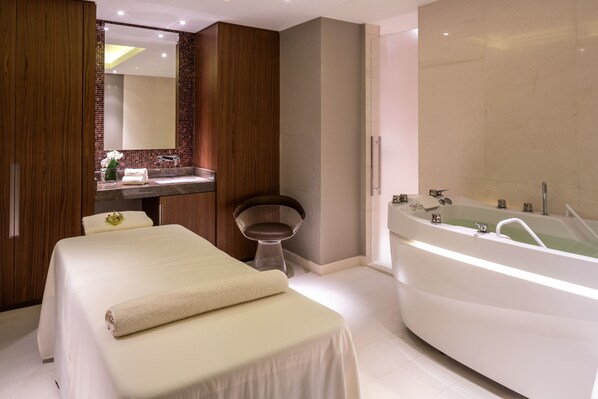 A modern bathroom with a large bathtub, a vanity with a mirror, and a bed with a towel. - Hilton Kyiv (Kyiv)