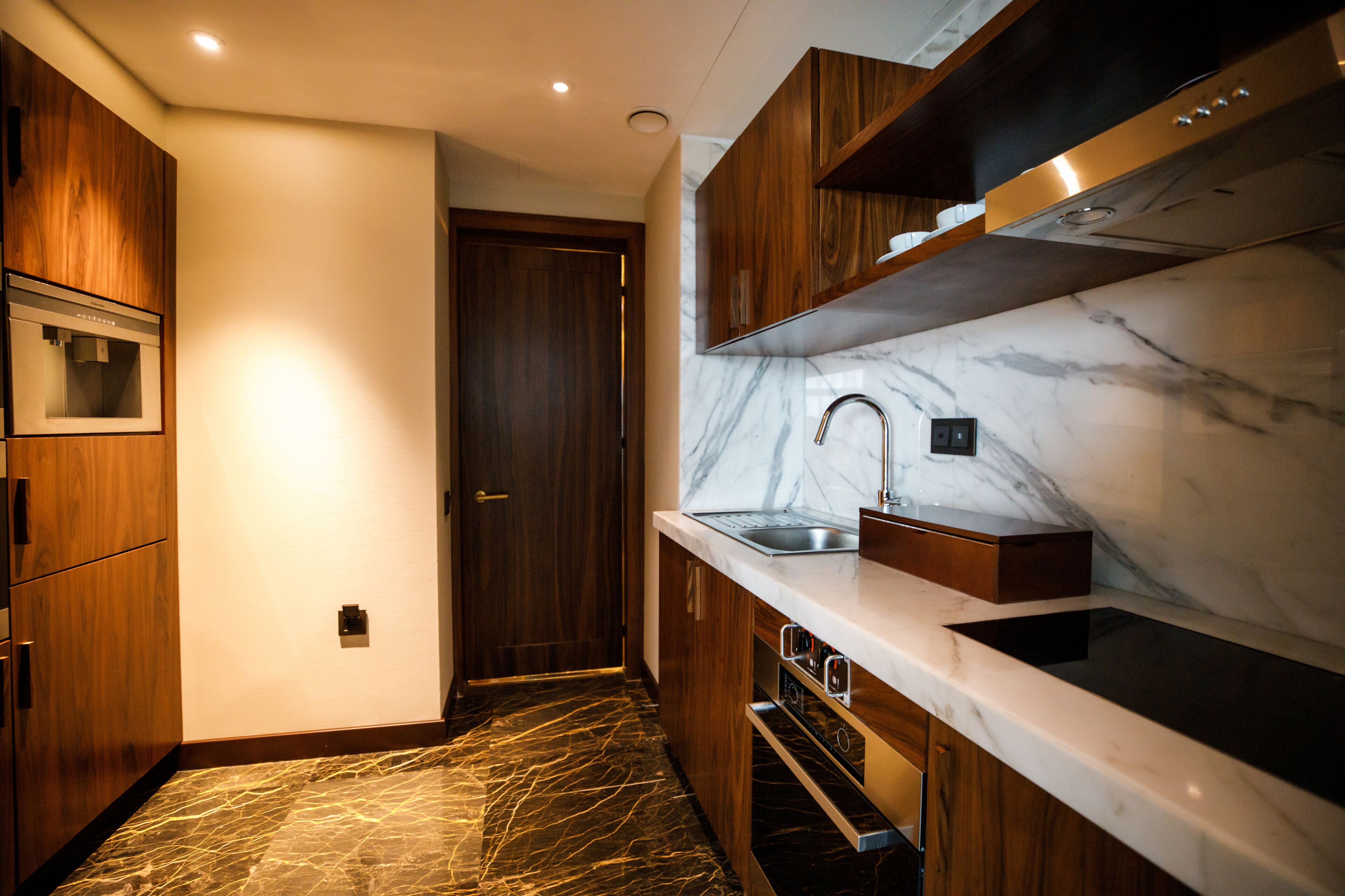 Una cocina moderna con armarios de madera, salpicadero de mármol y electrodomésticos de acero inoxidable.