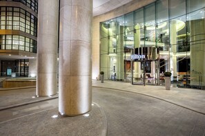 A modern hotel entrance with a glass facade, large columns, and a well-lit interior. - Hilton Kyiv (Kyiv)