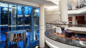 A modern hotel lobby with a glass atrium, a circular seating area, and a high ceiling with decorative lighting. - Hilton Kyiv (Kyiv)