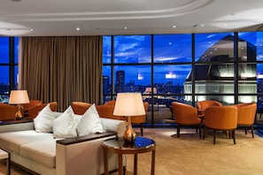 A modern hotel room with a city view, a sofa set, and a round table with lamps. - Hilton Kyiv (Kyiv)